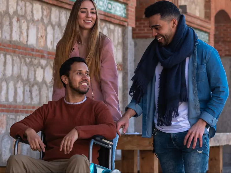 Man in wheelchair smiling with two friends