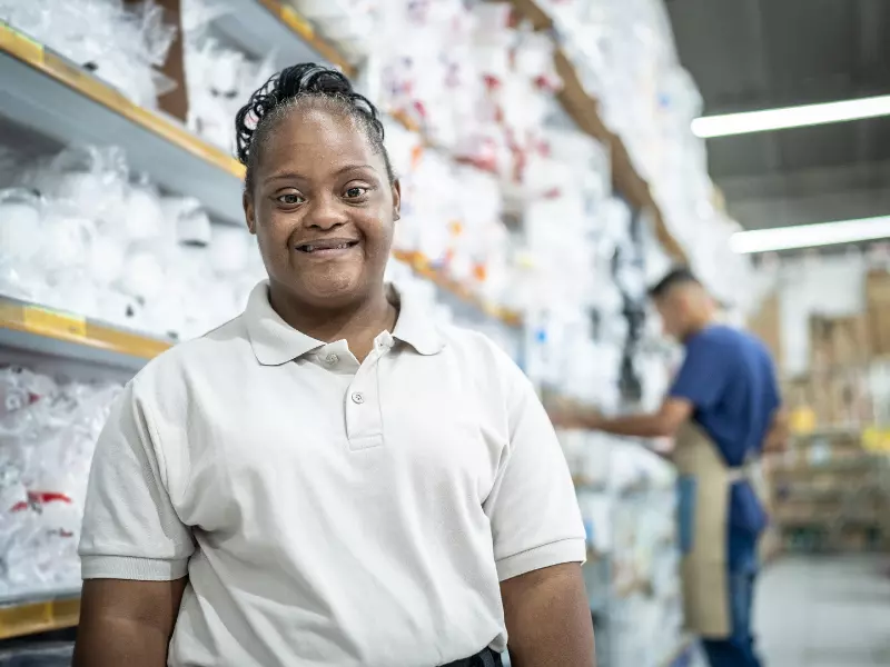 Girl with down syndrome smiling at camera while standing in shop