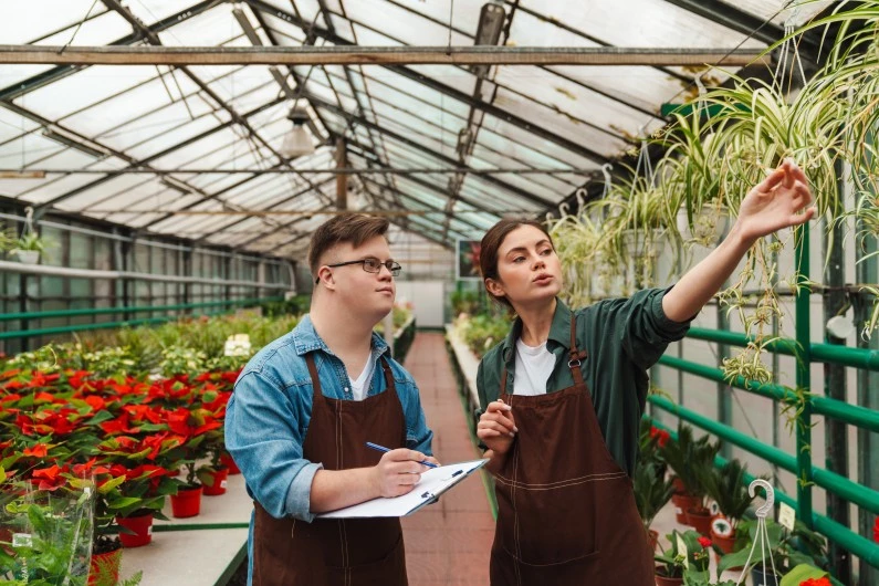 Man with down syndrome working with colleague in garden centre