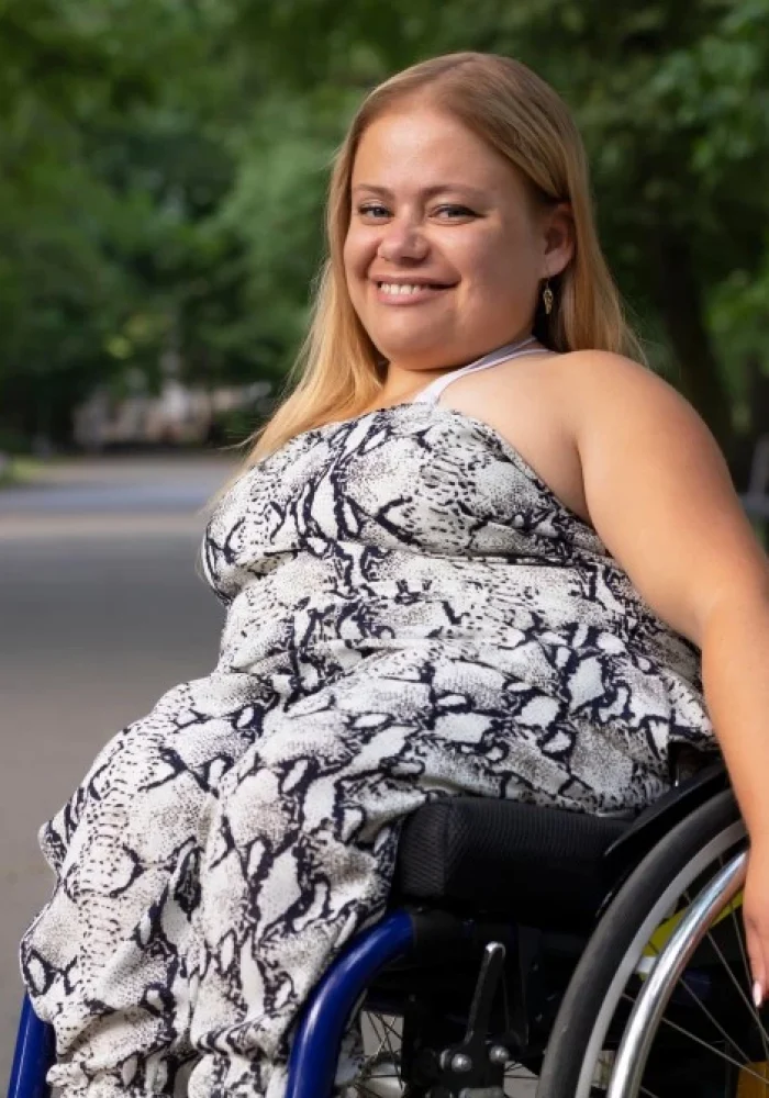 Woman in wheelchair in park smiling at camera